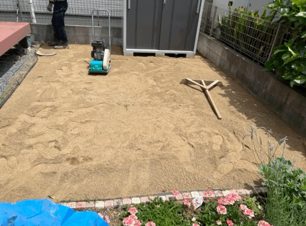 水はけをよくするために、人工芝を敷く前に砂を入れている写真。
